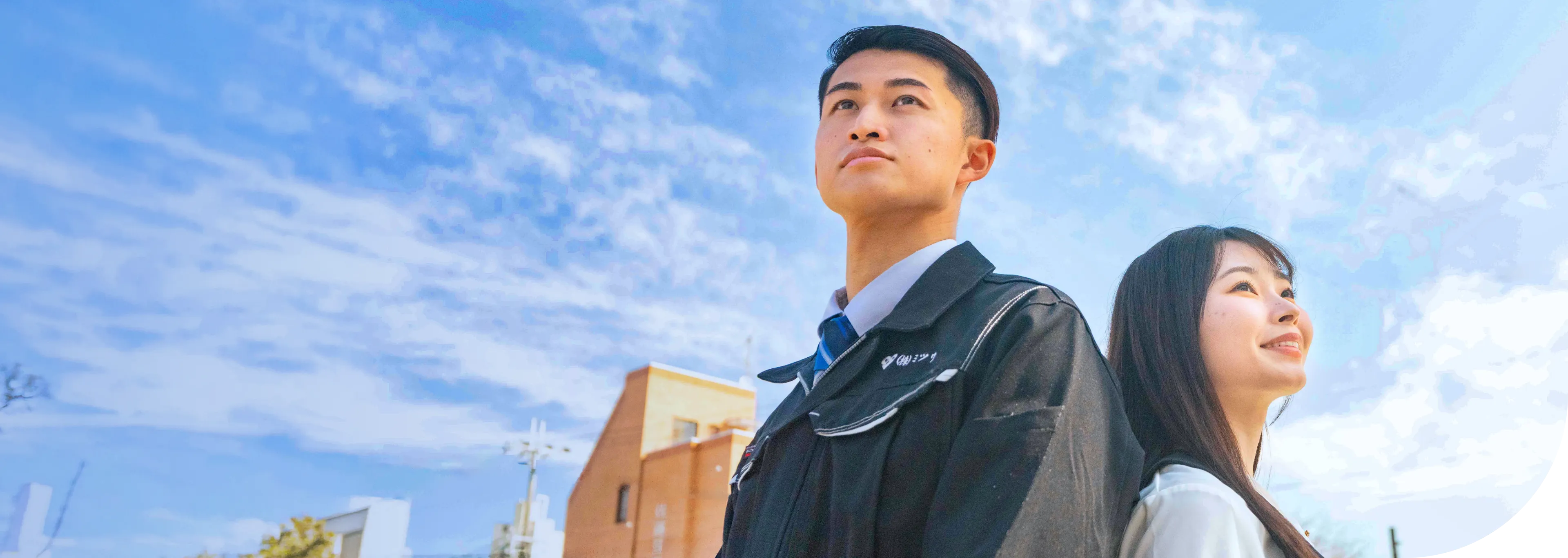 男性スタッフと女性スタッフが背中を寄せ合って空を見上げている様子